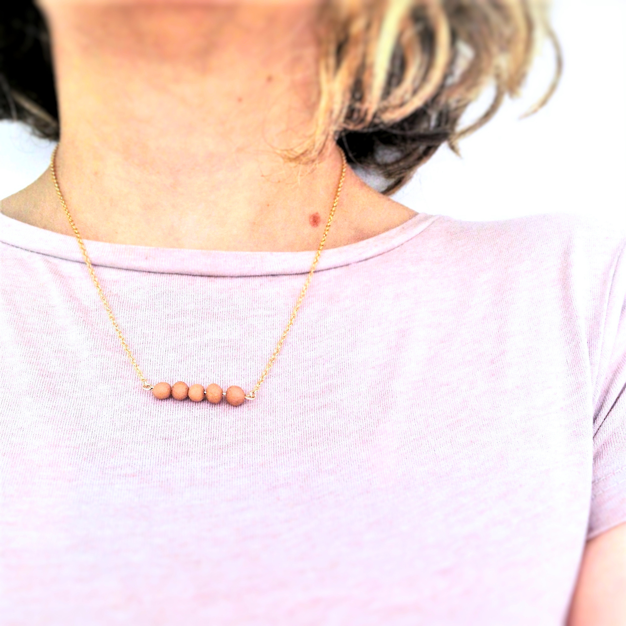 Collier perles argiles terracotta porté sur tshirt rose poudré