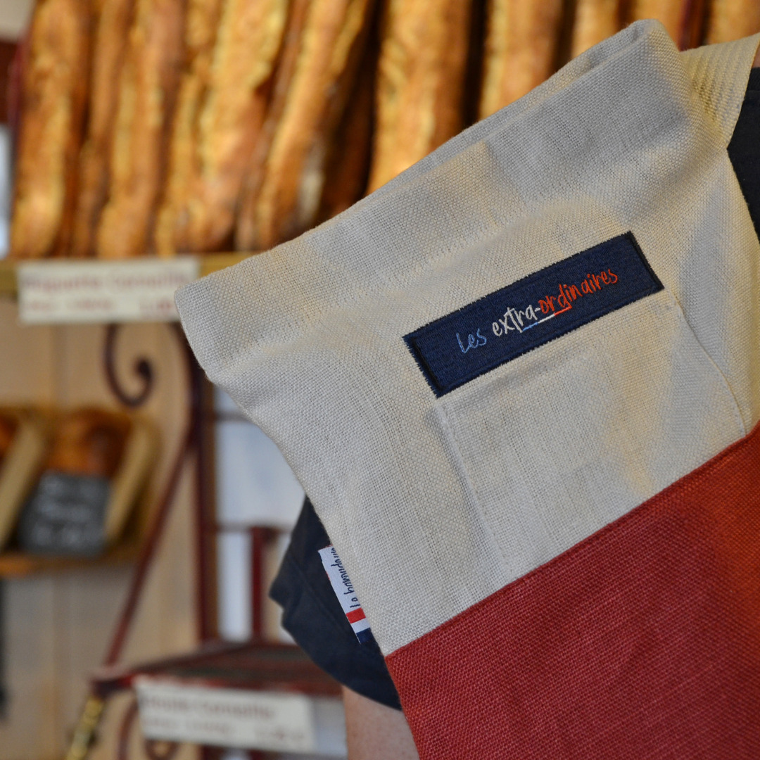 Sac à pain le baroudeur rouge devant des baguettes en boulangerie