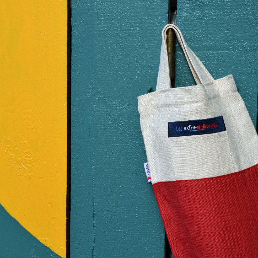 Sac à pain le craquant rouge accroché sur une palissade en bois