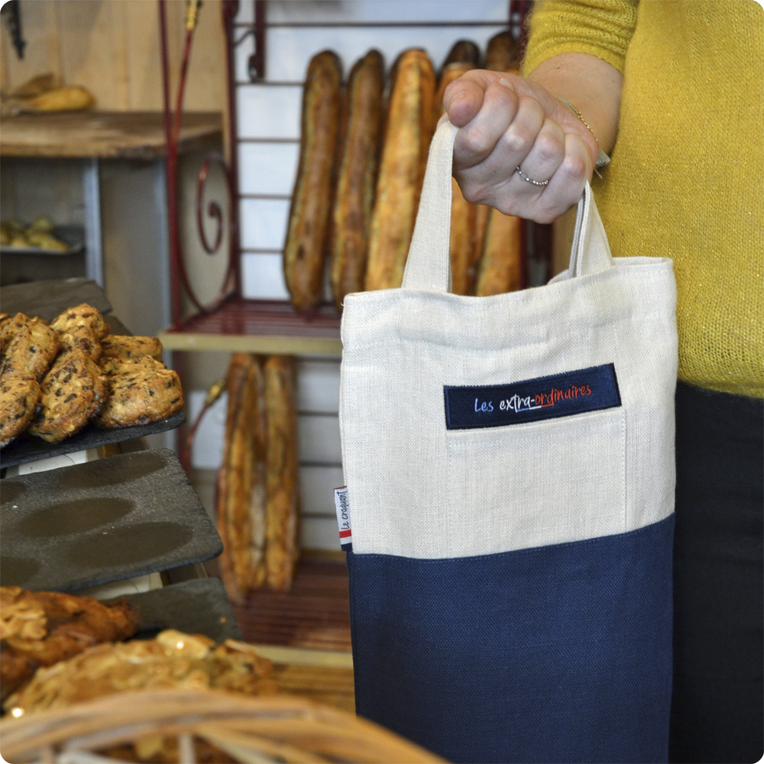 Sac à pain le craquant bleu tenu par une femme en boulangerie
