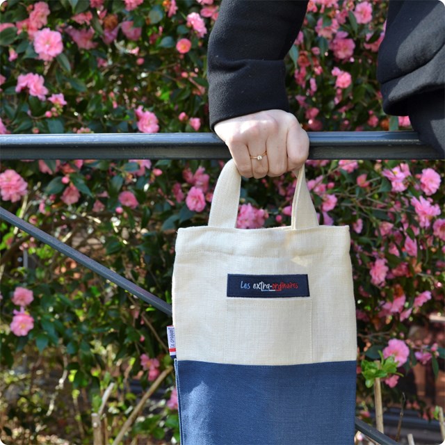 Sac à pain le craquant bleu tenu par une femme devant un buisson en fleurs