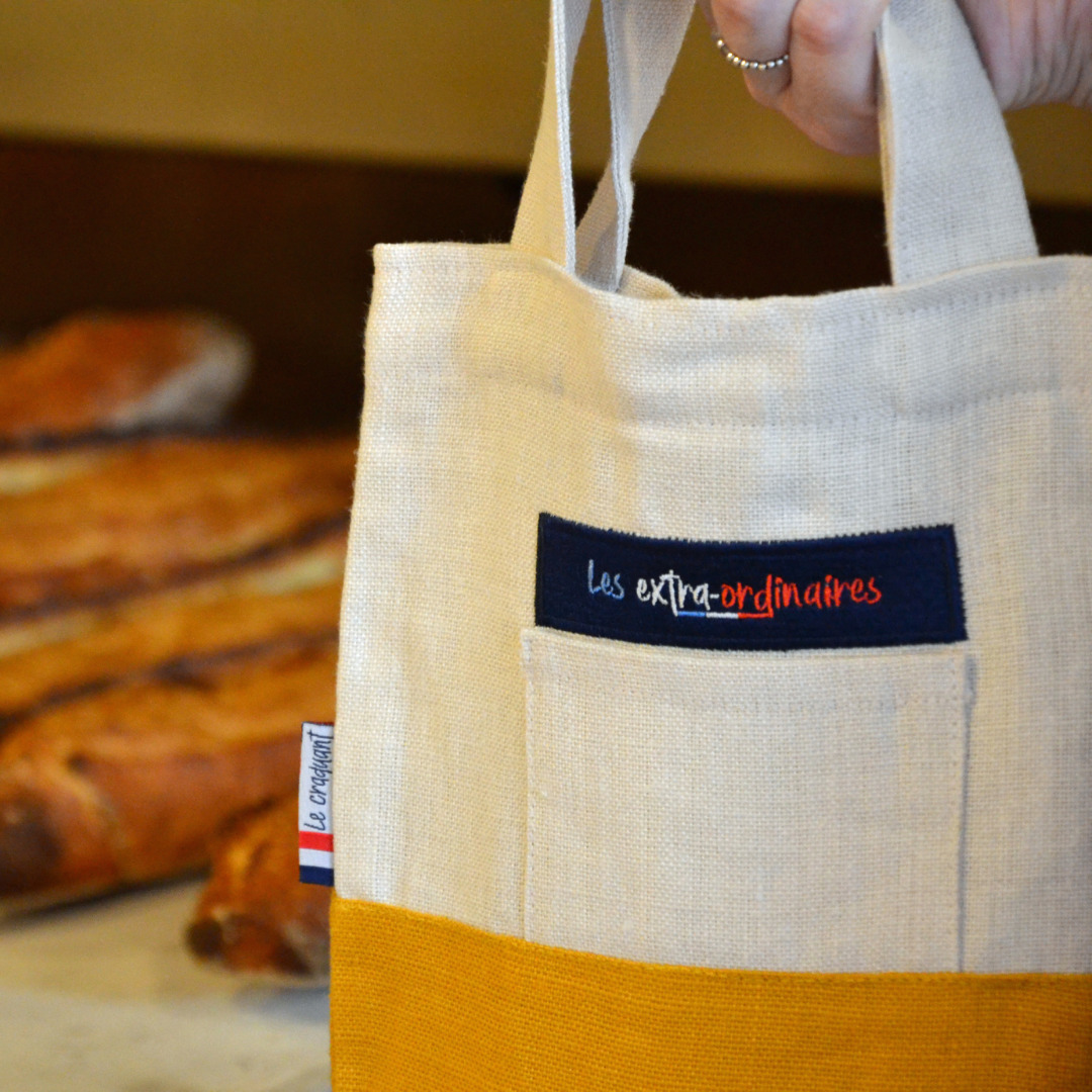Sac à pain le craquant jaune devant des baguettes de tradition