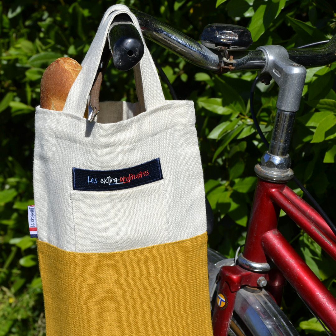 Sac à pain le craquant jaune accroché au guidon d'un vélo