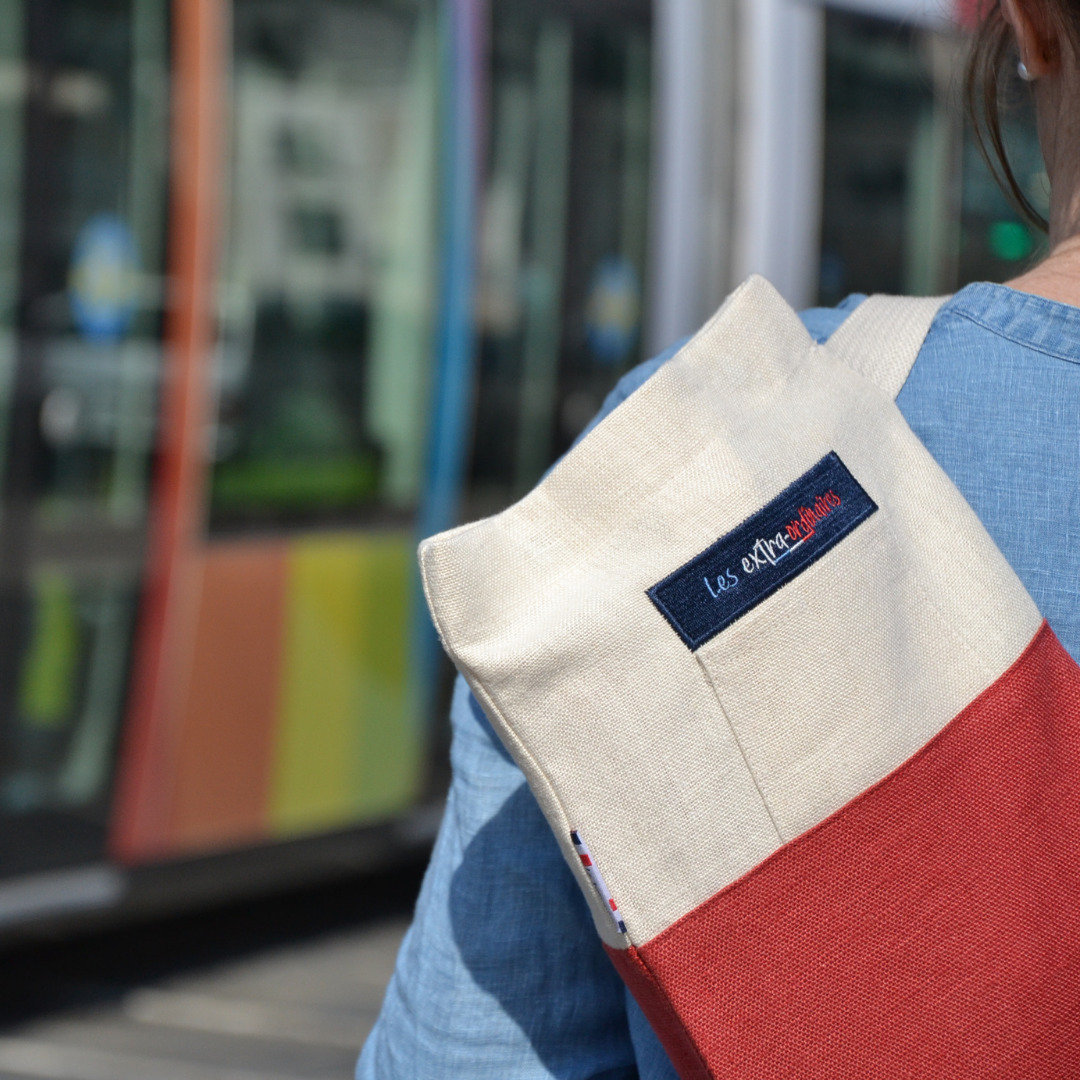 Sac à pain le baroudeur rouge porté par une femme devant un tramway