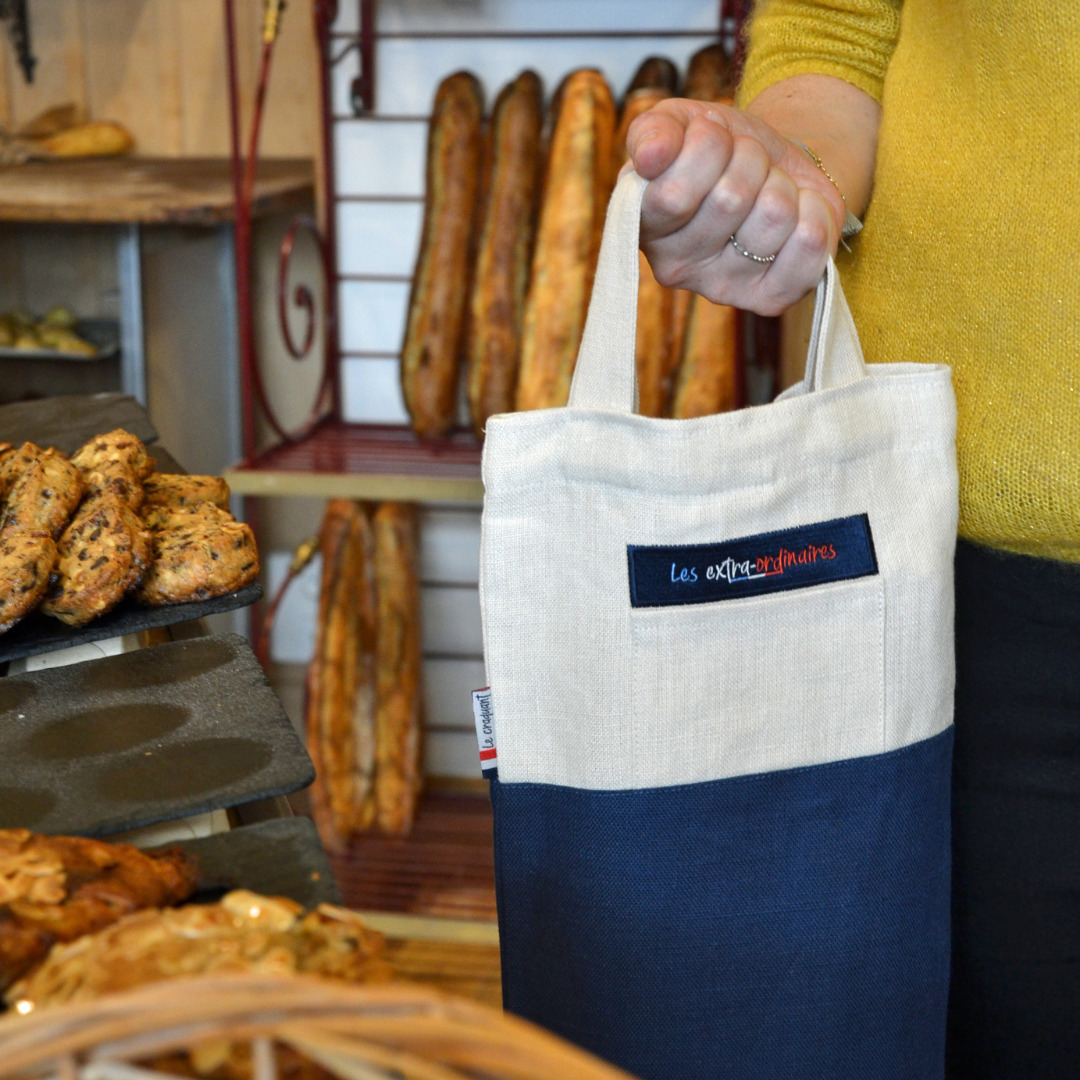 Sac à pain le craquant bleu tenu par une femme en boulangerie
