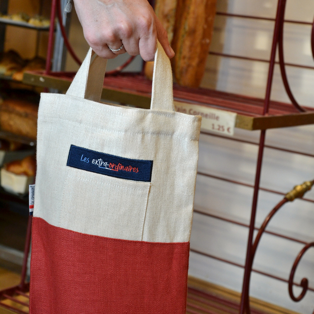 Sac à pain le craquant rouge tenu par une femme en boulangerie