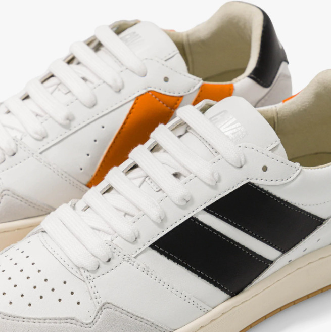 Baskets asymétriques dans les couleurs noires et orange, lacets blancs, logo brodé à l'arrière